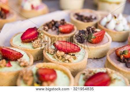 Background Filled With Colorful Cakes And Desserts With Fresh Fruits. Assorted Different Mini Cakes 