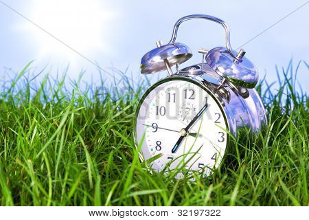 Foto von einer Chrom-Wecker im Freien sitzen im Gras am Morgen von einem sonnigen Tag.