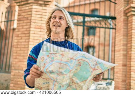 Young scandinavian tourist man smiling happy using map at the city.