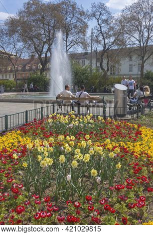 Graz, Austria-april 25, 2021: People Relaxing Near The Fountain In Jakominiplatz Square In The City 