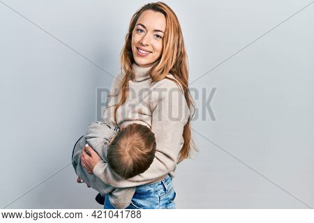 Young caucasian woman holding and hugging her son breastfeeding him, maternity lactation