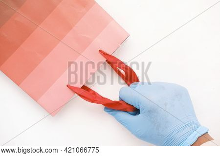 Hand In Latex Gloves Holding Red Color Shopping Bag On White Background