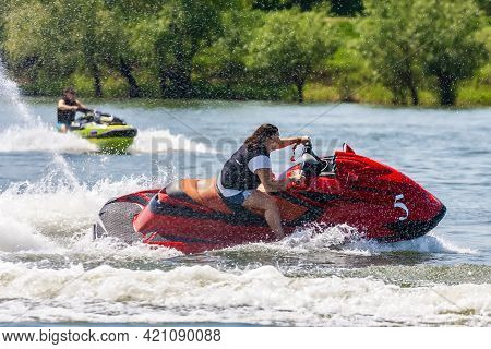 Krasnodar, Russia - July 25, 2020: Young Happy Caucaisian Woman Drives Jet Ski Splashing At Sunset B