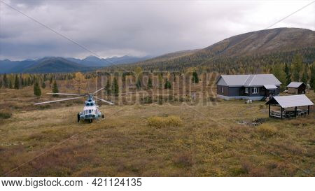 Aerial View Of A Helicopter Ready To Take Off From An Autumn Field With Rare Pine Trees And Forested