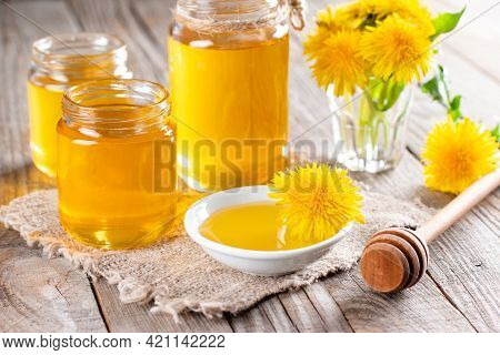 Homemade Healthy Dandelion Syrup In A Glass Bottle, Decorated With Fresh Flowers On Rustic Wooden Ba