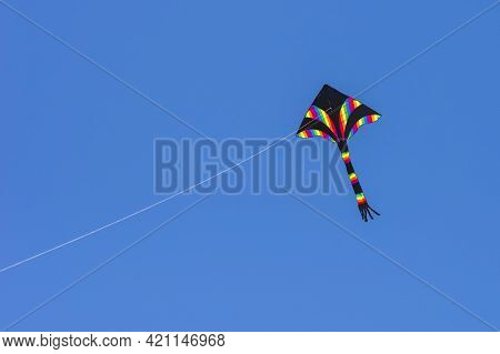 A Rainbow Colors Kite (delta Shape) Flying In The Blue Sky