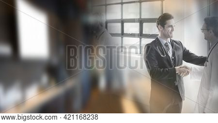 Composition of two smiling male doctors shaking hands in office with double exposure. healthcare, partnership and success concept digitally generated image.
