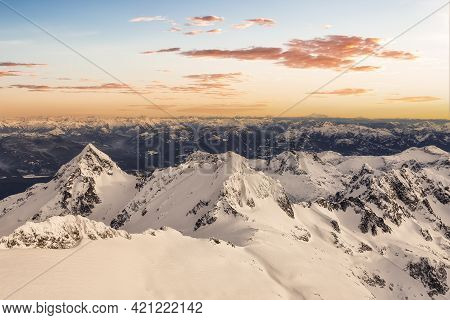 Aerial View From Airplane Of Blue Snow Covered Canadian Mountain Landscape In Winter. Colorful Orang