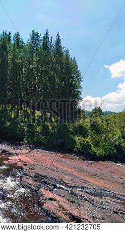 Beautiful Scenery Of A Pine Forest Over A Scenic Stone Plain Where An Attractive Waterfall Begins - 