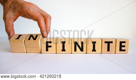 Finite Or Infinite Symbol. Businessman Turns Wooden Cubes And Changes The Word 'finite' To 'infinite