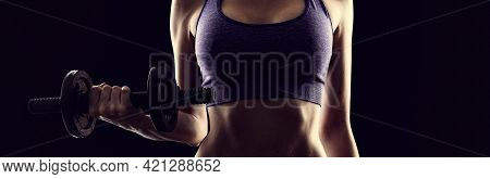 Slim Athletic Woman Holding Dumbbell In The Hand On Black