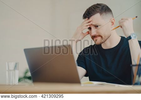 Worried Depressed Businessman Or Office Worker Holding Pencil And Nervously Looking At Laptop Displa