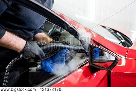 Car Service Worker Cleans Interiror With Steam Cleaner