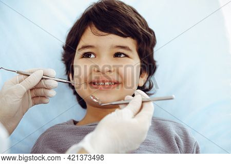 Cute Arab Boy Sitting At Dental Chair With Open Mouth During Oral Checking Up With Doctor. Visiting 