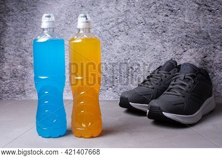 Two Bottles Of Isotonic Drink, Restoring Water And Salt Balance After Exercise On A Gray Background,