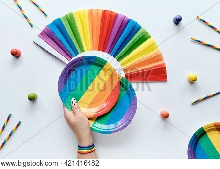 Lgbtq Community Pride Month Rainbow Concept Flat Lay. Hand With Ribbon Holds Paper Plate. Rainbow Fa