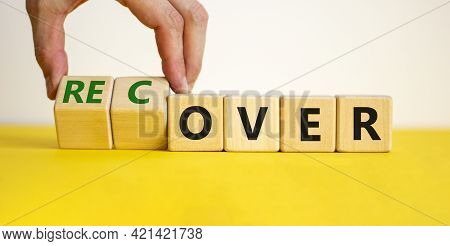 Time To Recover Symbol. Businessman Turns Wooden Cubes And Changes The Word 'over' To 'recover'. Bea