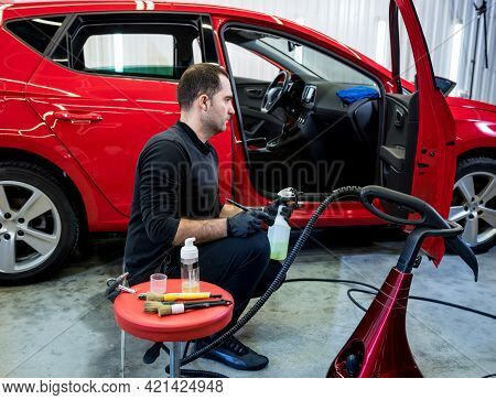 Car Service Worker Cleans Interiror With Special Brush