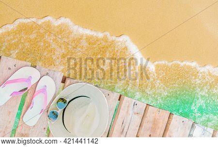 Top View Of Pink-white Sandals, Straw Hat And Sunglasses On Wooden Bridge Over Emerald-green Sea Wat