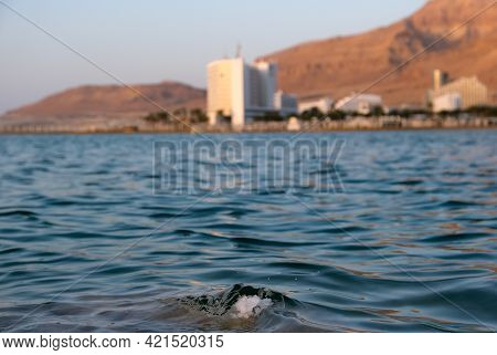 Salt Crystals On The Dead Sea Coast During Sunrise On Background Of Hotels