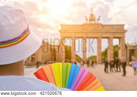Mature Caucasian Lgbt Woman In Berlin With Rainbow Fan And Ribbon On White Summer Hat. Rainbow, Symb