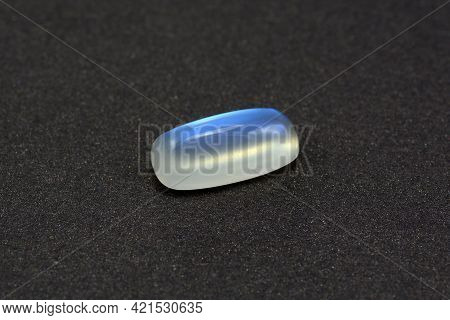Natural Genuine Adularia Blue Sheen Barrel Cabochon Moonstone. Loose Clean Crystal Gem On Gray Textu