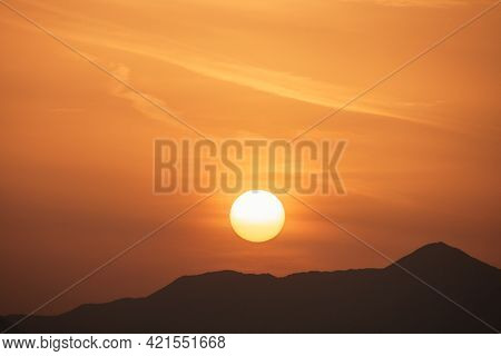 Sunset Sky With Orange Clouds. A Beautiful, Colorful, Abstract Mountain Landscape With Sun In A Oran