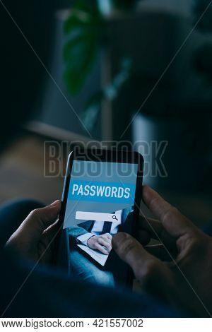 closeup of a young caucasian man, at home, using a password manager in his smartphone, with a simulated password manager app in its screen