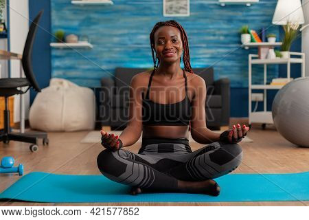 Portrait Of Black Woman Smiling Practicing Yoga At Home Sitting In Lotus Pose On Mat Mediting, Pract