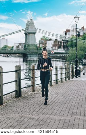 Beautiful Young Slim Woman Is Jogging Along The Embankment Of The River In London. Stay Healthy, Do 