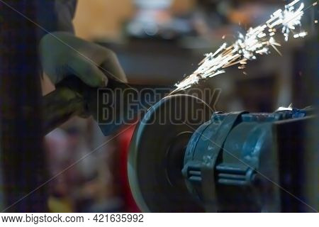 Sharpen The Axe Tool On The Rotating Grinding Wheel, Sparks Fly From The Metal.