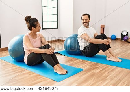 Mature hispanic couple doing excersice and stretching at yoga room. Two adult people doing pilates and flexibility workout