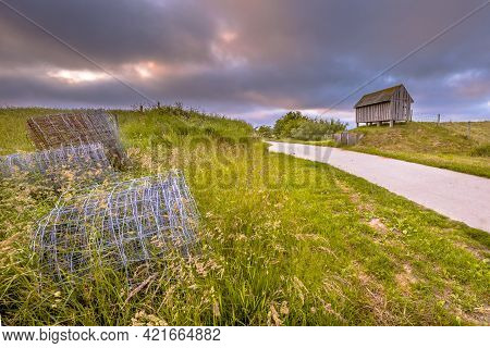 Road Passage Through Old Sea Dike At Sunset Under Beautiful Clouded Sky. Usquert, Groningen Province