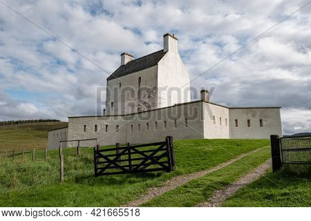 Landscape With White Corgarff Castle And A Wooden Fance In Scottish Countryside At Nice Sunny Aftern