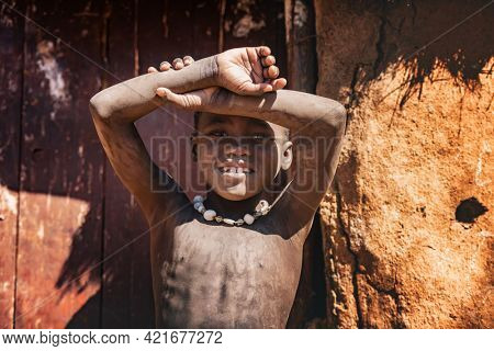 OPUWO, OTJIWARONGO REGION NAMIBIA - MAY 4, 2021: Young unidentified Himba boy with the typical necklace in Himba living museum during a appearance in front of tourists
