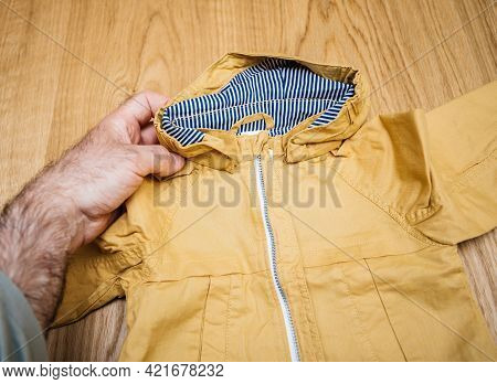 Lyon, France - May 2, 2021: Pov Male Hand Father Holding Infant Winter Fall Rain Jacket Baby Clothes