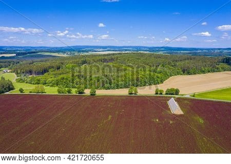Red blooming crimson clover field (Trifolium incarnatum) and heap of bales seen from above