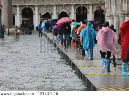 Many People Walk On The Elevated Walkway During High Tide In Venice With Gaiters On Their Feet And R