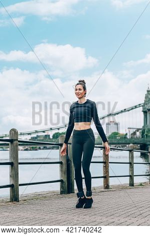 Beautiful Young Slim Woman Is Jumping During Sport Activities Along The Embankment Of The River In L