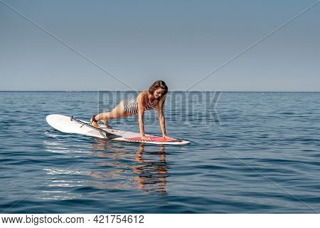 Sporty Girl On A Glanders Surfboard In The Sea On A Sunny Summer Day. In A Striped Swimsuit, It Is I