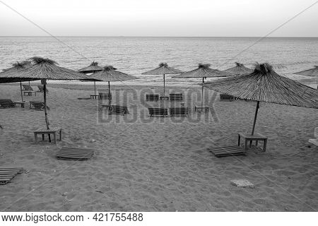 Beach View With Straw Umbrellas In Black And White. Seasonal Natural Background.