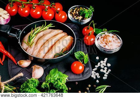 Chicken Fillet In A Skillet With Spices And Vegetables On A Dark Background. Raw Chicken Meat Cut In