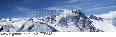 Panorama Of High Snow-capped Mountain Peaks And Beautiful Blue Sky With Clouds At Sun Windy Day. Cau