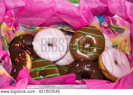 Box With A Bulk Of Different Type Of Colorful Tasty Gluten Free Doughnut Surround By Pink Paper Wrap