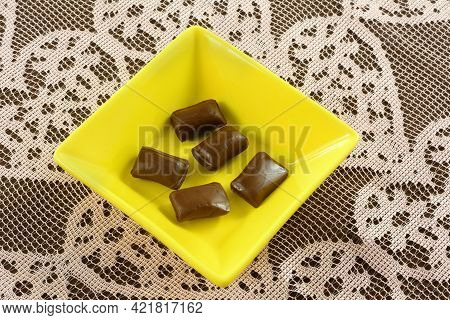 Chocolate Taffy Snack Candy Pieces In Yellow Candy Dish On Pink Lace Heart Tablecloth