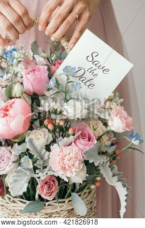 Hand carrying a basket filled with assorted colorful flowers and a note card