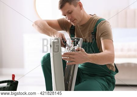 Professional Technician Repairing Electric Ultrared Heater With Pliers Indoors