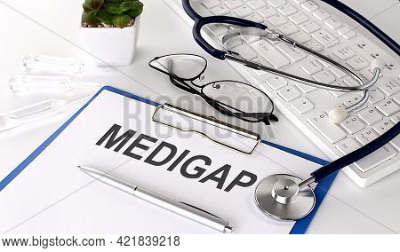 Medigap Text On White Paper On The White Background. Stethoscope ,glasses And Keyboard