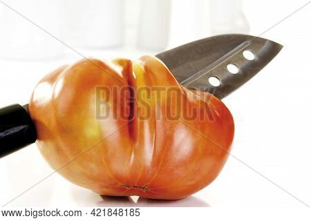 Close Up Of Oxheart Tomato And Knife On White Background