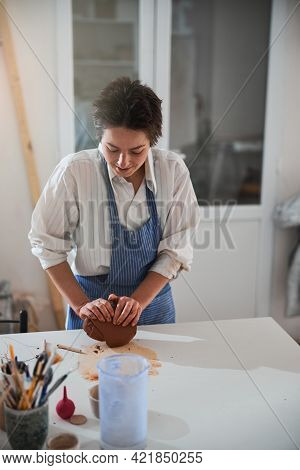 Pleased Brunette Woman Working With A Piece Of Fireclay